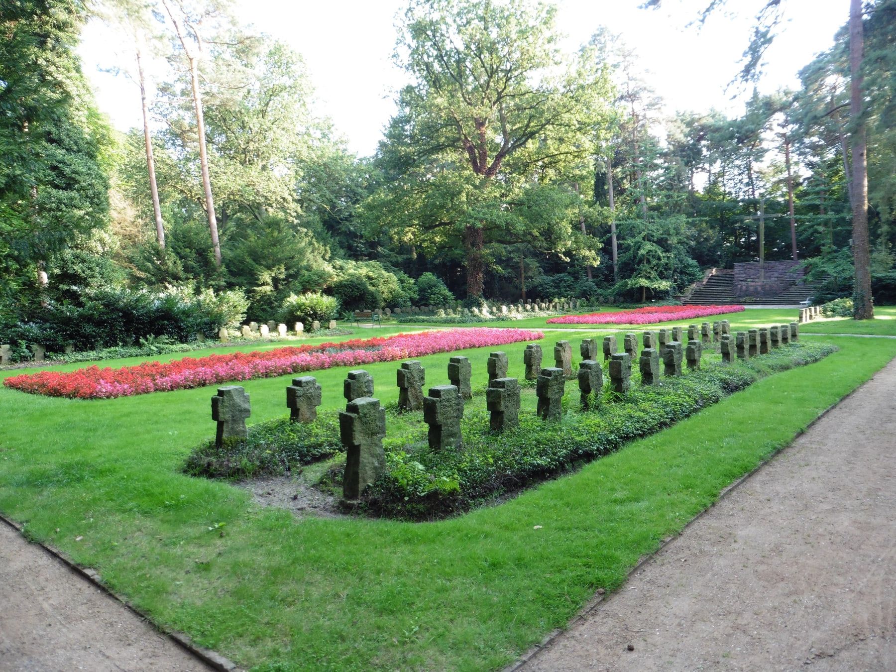 Steinerne Kreuze und farbige Blumenbänder auf der Kriegsgräberstätte auf Friedhof Bergedorf
